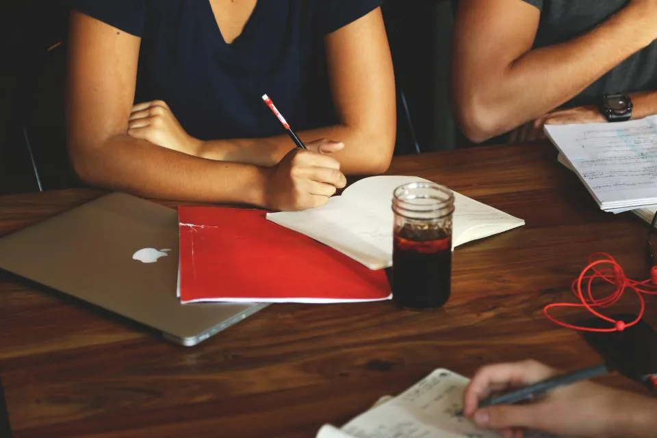 Personas colaborando frente a una laptop con documentos sobre la mesa