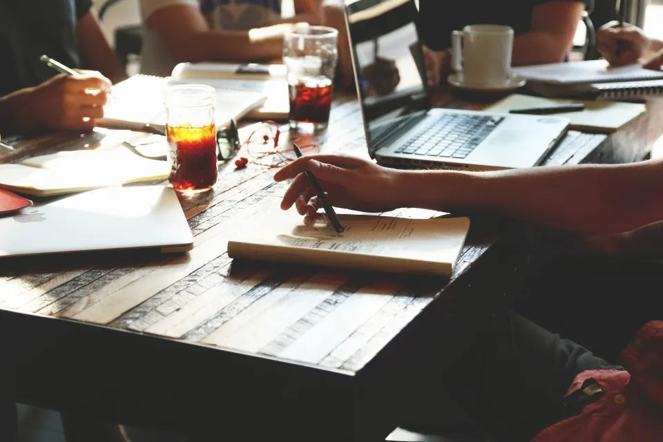 Personas revisando papeles y una laptop en una mesa de trabajo